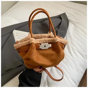 Detail of brown suede bucket bag with white faux fur trim and silver buckle closure