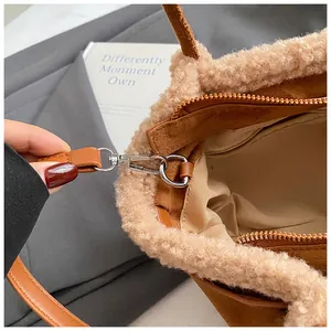 Detail of suede bucket bag with shearling trim and detachable brown leather strap