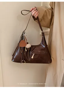 Détail du sac hobo marron foncé brillant avec pendentif cœur et breloque en peluche