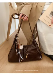 Détail d'un sac porté épaule en cuir marron avec pendentif noix et fermoir blanc