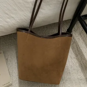 Minimalist brown suede bucket bag with long shoulder straps for stylish daily commute