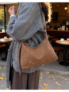 Brown faux suede hobo bag with fringe details shown in a cozy autumn street setting