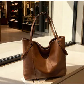 Close-up of brown leather tote bag texture featuring metallic rivet detail and handles