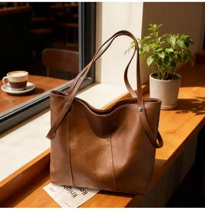 Close-up of brown faux leather tote bag with metallic rivet details on a cafe window sill