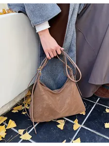 Detail of caramel suede tote bag with golden metal buckle and slim shoulder strap