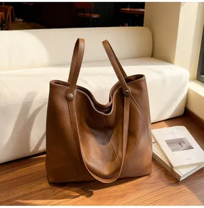 Close-up of brown leather tote bag texture and metal buckle on wooden floor