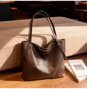 Detail of dark brown leather tote bag with vertical stitching on soft fabric sofa