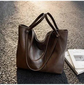 Close-up of deep brown tote bag showing smooth leather texture and silver rivet details