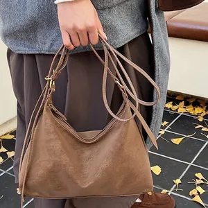 Brown faux suede hobo tote bag for women worn over shoulder with autumn leaves background