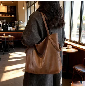 Detail of dark brown tote bag showing smooth leather texture and metal strap buckle