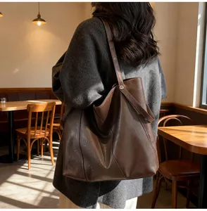 Brown faux leather tote bag worn by a model in a cozy cafe setting for daily commuting