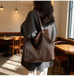 Detail view of deep brown leather tote bag showing side buckle on female model
