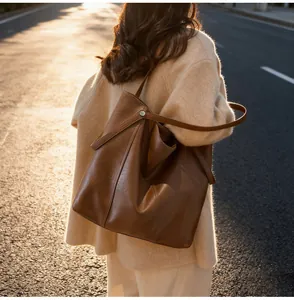 Detail of dark brown tote bag with smooth texture shown in a street fashion style