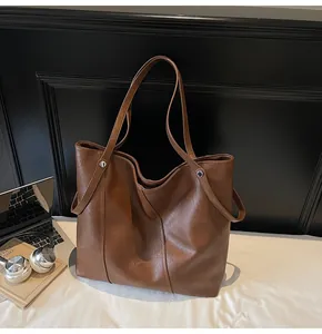 Brown faux leather tote bag detail showing dual straps and silver rivet accents