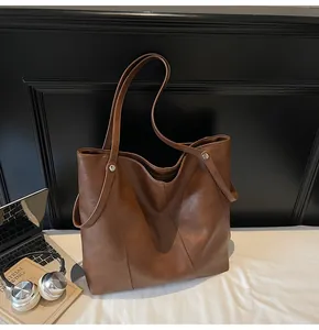 Detailed view of deep brown textured tote bag with metal rivet accents and soft draping