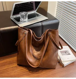 Close-up of brown pebbled leather tote bag with round metal hardware detail