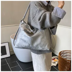 Detailed view of silver metallic tote bag featuring textured PU leather and gold buckles