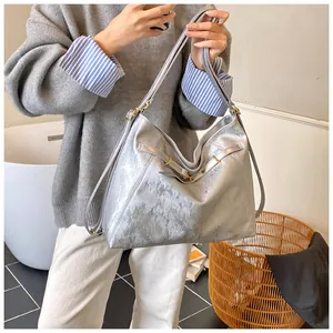 Close-up of silver metallic tote bag featuring gold hardware and chic strap details