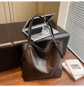 Detail of dark brown tote bag with retro PU leather texture and silver laptop
