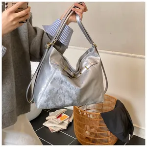 Detail of silver metallic tote bag featuring pleated texture and golden metal hardware