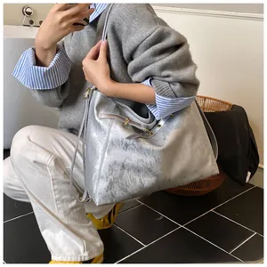 Detail of silver metallic tote bag with reflective texture and gold hardware on model