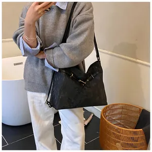 Close-up of black tote bag showing subtle textured pattern and elegant metal buckle detail