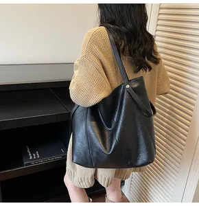 Close-up of the large black tote bag featuring geometric stitching and silver buckle detail