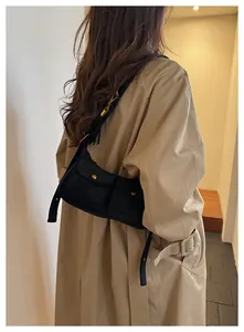 Detail of black multi-pocket shoulder bag with gold buckles on a beige trench coat