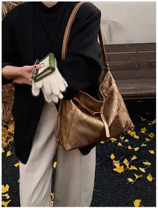 Detail of metallic bronze tote bag with vertical texture and golden hardware in autumn setting