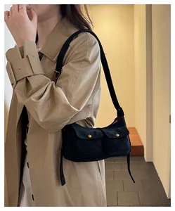 Detail of black suede shoulder bag with dual flap pockets and gold hardware buttons