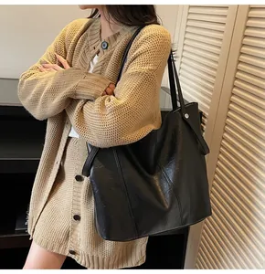 Close-up of black leather tote bag showing smooth texture and spacious interior on model