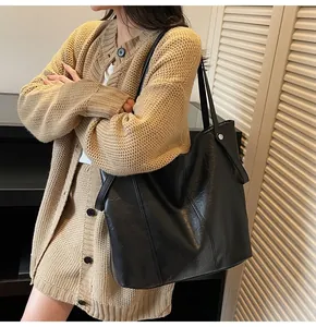 Close-up of black leather tote bag with lychee texture and silver stud details