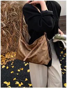 Detail of vintage bronze oversized tote bag with aged leather texture on female shoulder