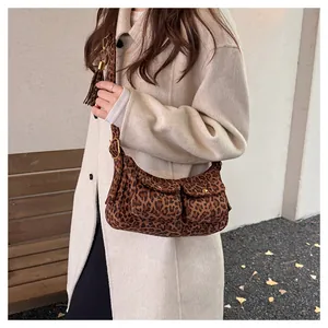 Detail of leopard print baguette bag featuring double front pockets and tassel charm