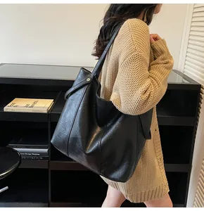 Detail of large black leather tote bag with silver rivets and vertical stitching