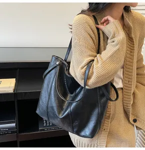 Detail of a large black tote bag showing its leather texture and shoulder strap fit