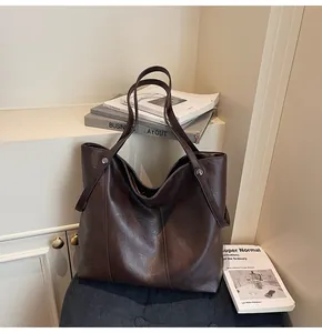 Close-up of vintage brown oil wax leather texture and metal rivets on the tote bag