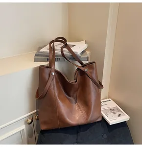 Close-up of brown faux leather tote bag showing fine texture and metal stud detail