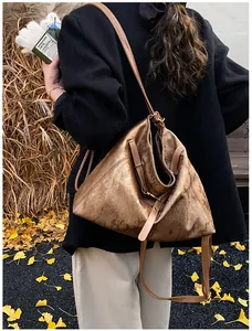 Detailed texture of bronze metallic tote bag with thin leather strap and buckle