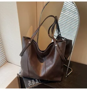 Detail of dark brown tote bag showing soft PU leather texture and silver metal rivets