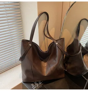 Close-up of a large dark brown tote bag showing smooth leather texture and stitching detail