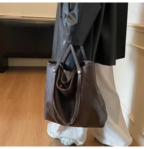 Detail view of large dark brown tote bag showing smooth leather texture and silver rivets