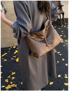 Detail of a large brown leather tote bag with vintage texture and gold buckle accents