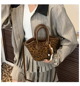 Detail of leopard print bucket bag with brown leather handles and beaded charm accessory