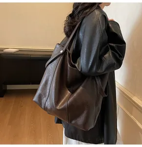 Close-up of the dark brown tote bag with side silver metal buckle and soft leather texture