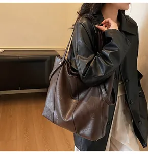Detail of a large dark brown faux leather tote bag with vintage texture and sleek straps