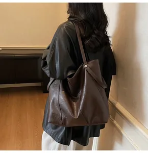 Detailed view of dark brown leather tote bag showing natural grain texture and long strap