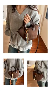 Detail view of deep brown suede tote bag with beaded pendant and embossed logo