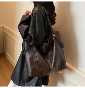 Detail view of large dark brown tote bag with metal rivets on minimalist PU leather