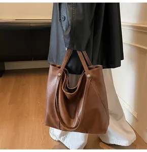 Brown leather tote bag featuring natural texture and metal rivet detail for daily commute